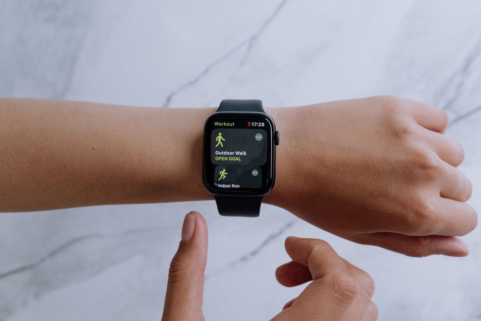Apple Watch with a black band showing workout options on a person's wrist